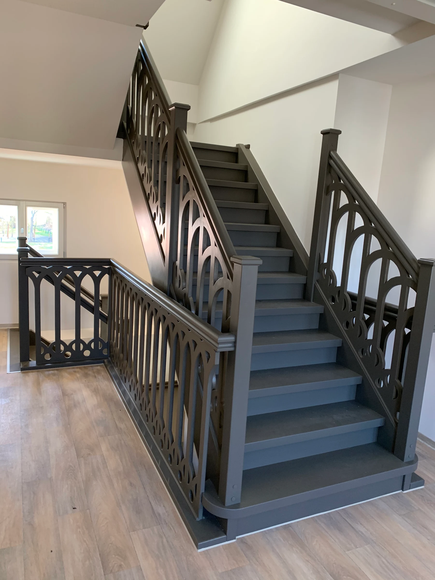 Historische graue Holztreppe mit ornamentiertem Geländer